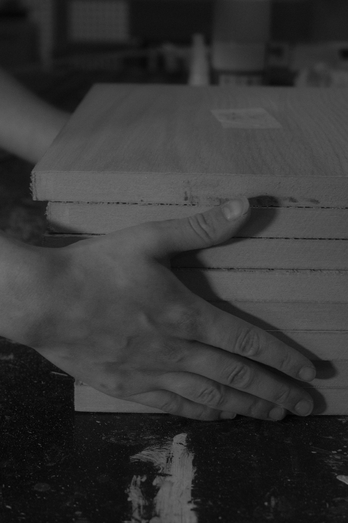 Hands selecting timber boards in the workshop