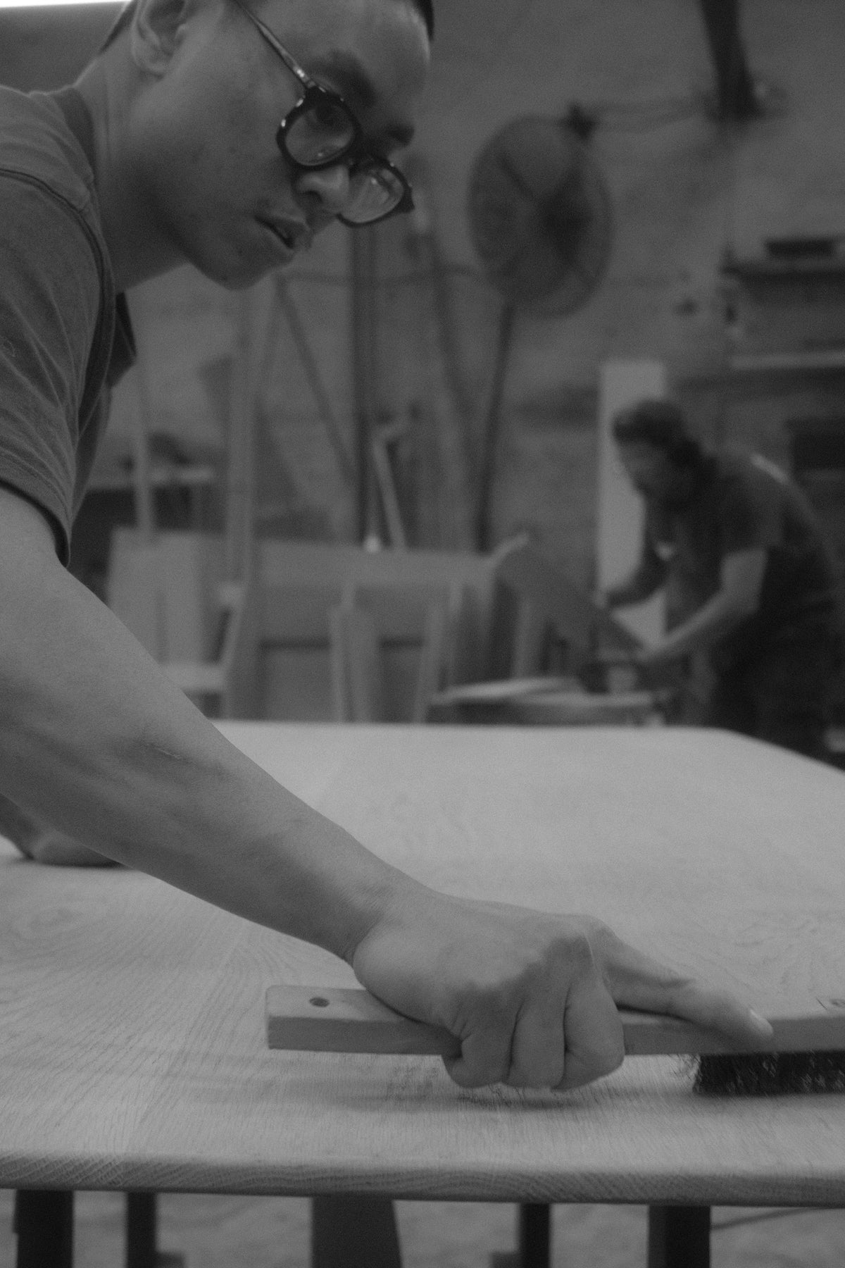 A maker brushing the surface of a timber panel